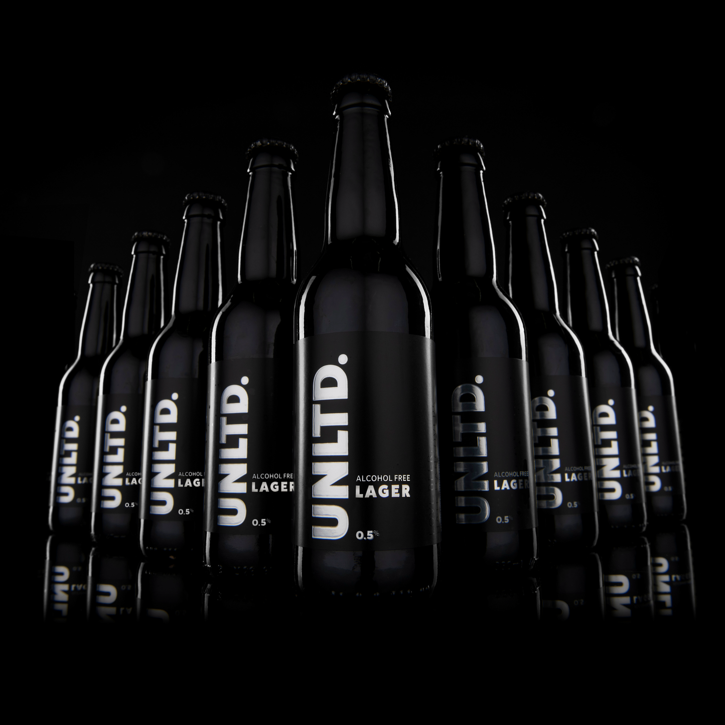 Bottles of UNLTD. Alcohol Free Lager on a black background